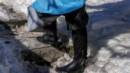 Masrat Farid, seorang petugas kesehatan yang mengenakan sepatu bot kulit, berdiri di atas tangga yang tertutup salju selama upaya vaksinasi COVID-19 di Gagangeer, timur laut Srinagar, Kashmir yang dikuasai India, pada 12 Januari 2022. (AP Photo/Dar Yasin)