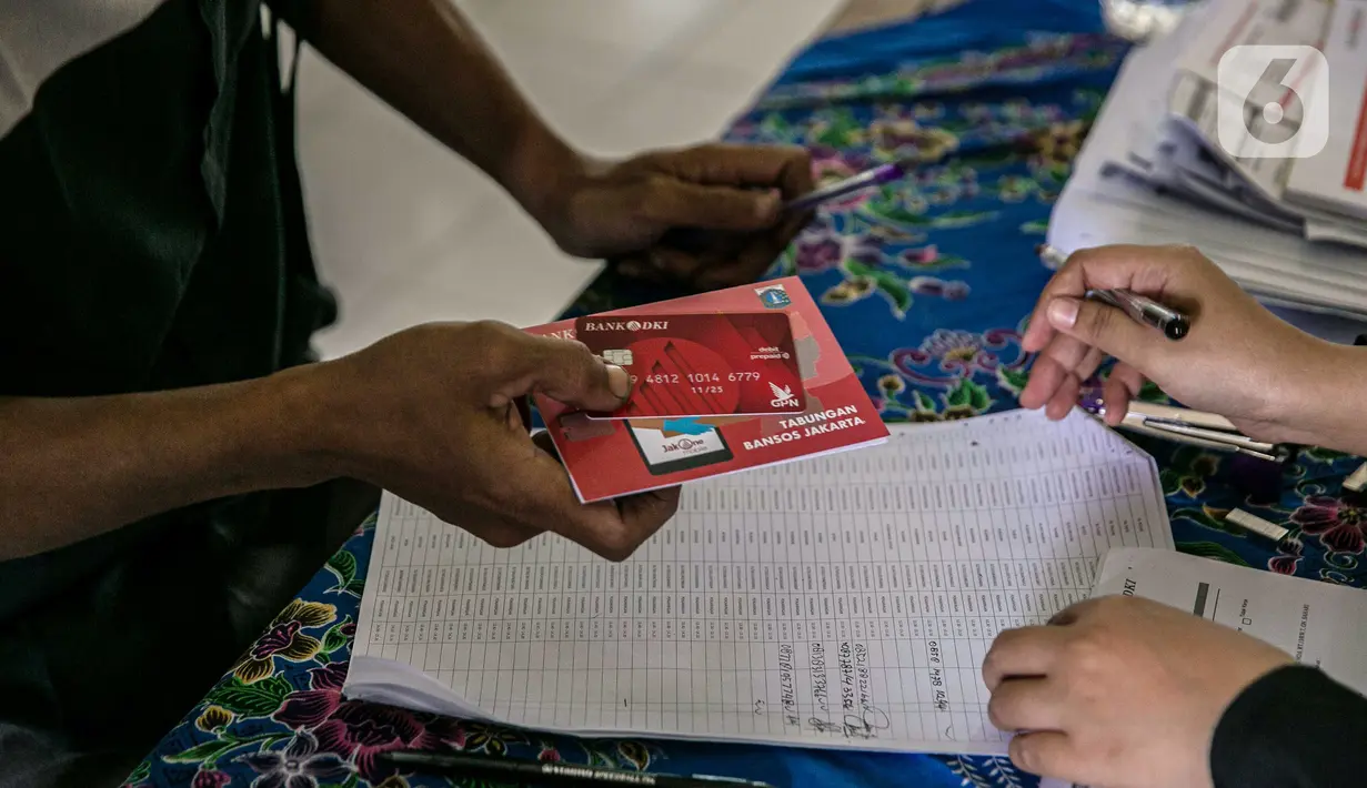 Warga menerima buku tabungan dan ATM saat mengambil Bantuan Sosial Tunai (BST) di SMAN 111, Jakarta, Selasa (19/1/2021). Pemprov DKI Jakarta menyalurkan BST sebesar Rp 300 ribu kepada 1.055.216 KK mulai Januari hingga April 2021. (Liputan6.com/Faizal Fanani)