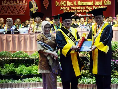 Mantan Wakil Presiden Jusuf Kalla (kiri) didampingi sang istri, Mufidah Kalla berjabat tangan dengan Rektor Universitas Negeri Padang (UNP) Ganefri (kanan) saat penganugerahan gelar doktor kehormatan (Dr. Honoris Causa), di kampus tersebut di Padang, Kamis (5/12/2019). (FOTO: Tim Media JK)