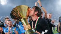 Pelatih Napoli, Antonio Conte, mencium trofi Serie A saat selebrasi juara Liga Italia musim 2024/2025 di Stadion Diego Armando Maradona, Sabtu (24/5/2025). (AP Photo/Gregorio Borgia)
