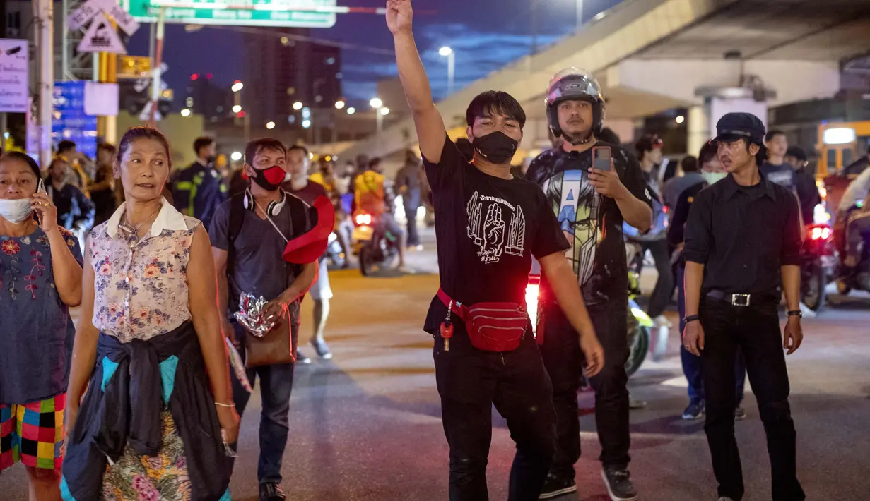 Sekelompok kecil demonstran pro-demokrasi memberikan penghormatan tiga jari kepada petugas polisi antihuru-hara dekat Gedung Pemerintah di Bangkok, Thailand, Kamis (15/10/2020). Polisi Thailand membubarkan demonstran yang berunjuk rasa di luar kantor perdana menteri. (AP Photo/Gemunu Amarasinghe)
