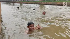 Anak-anak berenang di Sungai Kalimalang, Jakarta Timur, Jumat (5/7/2019). Tingginya suhu udara Ibu Kota akibat musim kemarau menyebabkan anak-anak tersebut berenang di Sungai Kalimalang meski dengan kondisi seadanya. (Liputan6.com/Immanuel Antonius)