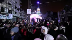 Sejumlah warga berkumpul saat perayaan malam Natal di kawasan Al-Hamidiyah kota tua Homs, Suriah, (24/12). Warga terpaksa merayakan malam Natal di tengah reruntuhan bangunan di daerah konflik tersebut. (REUTERS/Omar Sanadiki)
