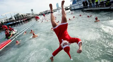 Seorang peserta dalam kostum sinterklas melompat ke air saat  kompetisi renang Copa Nadal di Port Vell Barcelona, Selasa (25/12). Lomba tradisional ini sudah menjadi tradisi lama yang mereka lakukan tiap tahun pada hari natal. (Josep LAGO / AFP)