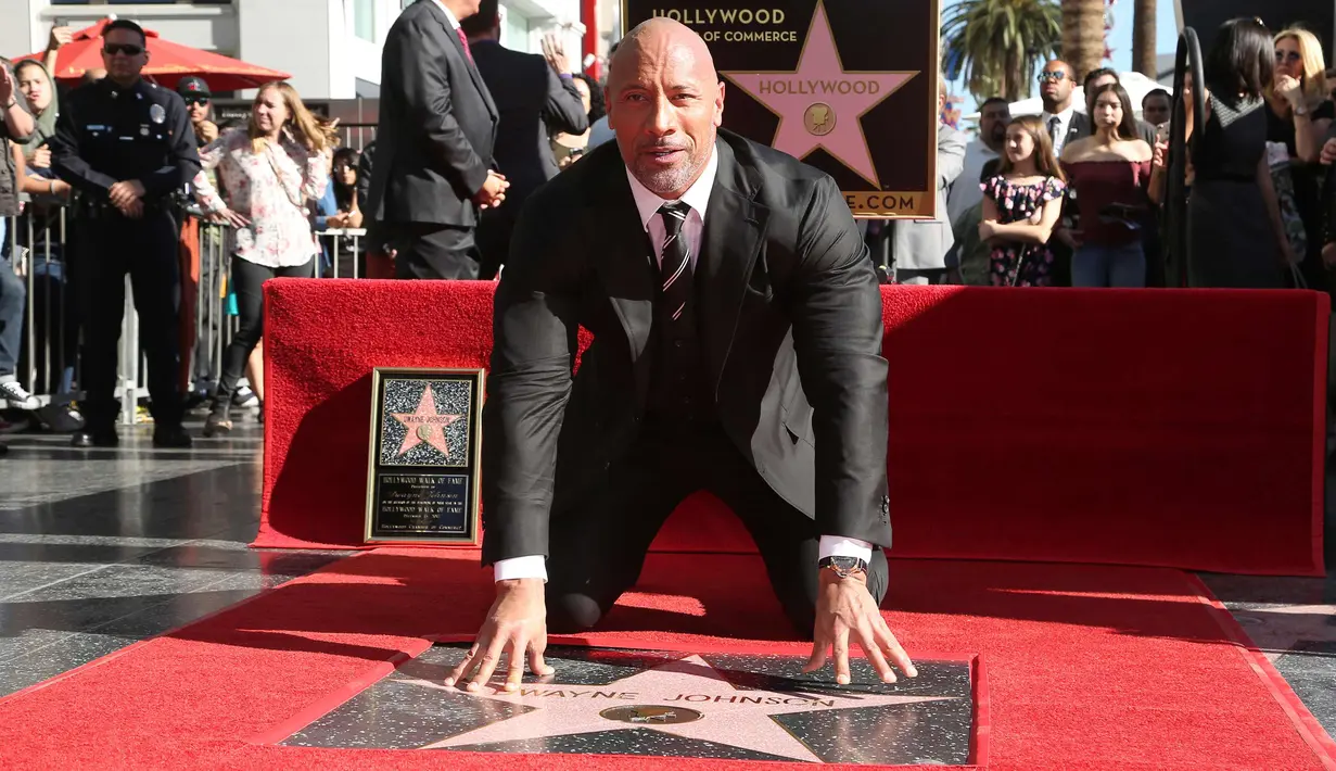 Dwayne Johnson berpose di sebuah plakat bintang atas namanya dari Hollywood Walk of Fame di Los Angeles, Jumat (13/12). The Rock mengungkapkan rasa bahagianya atas pemberian bintang ini lewat akun media sosialnya. (Photo by Willy Sanjuan/Invision/AP)