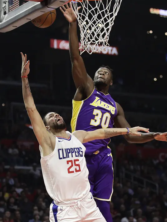 Pemain Clippers, Austin Rivers (bawah) melepaskan tembakan saat diadang pemain Lakers, Julius Randle pada laga NBA basketball games di Staples Center, Los Angeles, California, (27/11/2017). Clippers menang atas Lakers 120-115. (AP/Jae C. Hong)