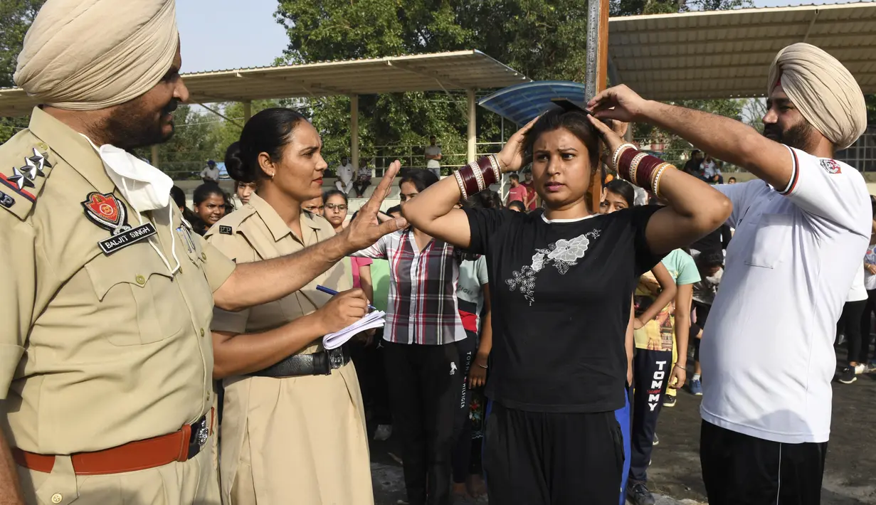 Petugas polisi Punjab mengukur tinggi badan seorang calon polisi wanita saat pelatihan calon polisi Punjab di Amritsar, India, Senin (28/6/2021). (AFP/Narider Nanu)
