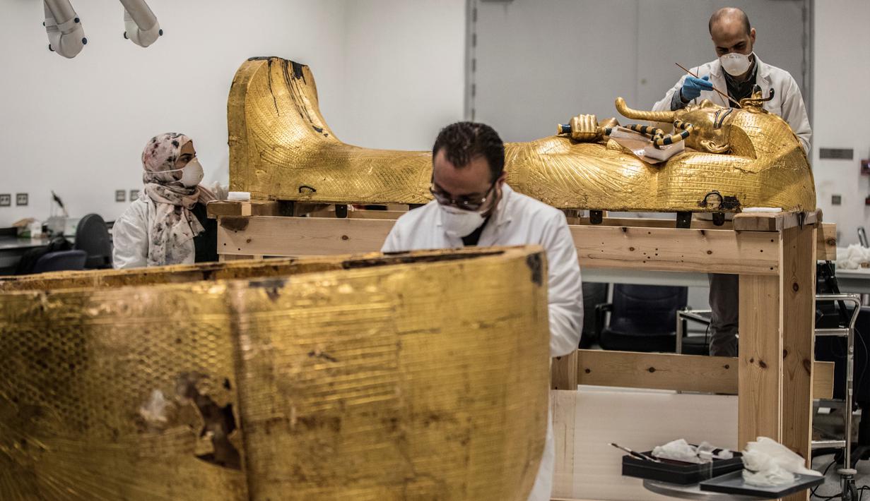 Para arkeolog merestorasi sarkofagus atau peti mati emas Firaun Tutankhamun di laboratorium restorasi Grand Egyptian Museum (GEM), Giza, Mesir, Senin (13/4/2020). Firaun Tutankhamun merupakan Raja Mesir Kuno yang memerintah antara tahun 1342-1325 SM. (Khaled DESOUKI AFP)