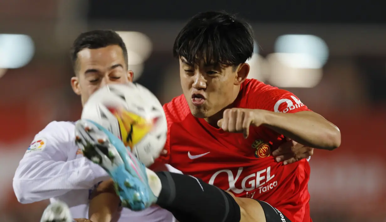 Gelandang Mallorca, Takefusa Kubo berebut bola dengan gelandang Real Madrid, Lucas Vazquez pada pertandingan lanjutan La Liga Spanyol di Palma de Mallorca, Spanyol, Selasa (15/3/2022). Madrid menang telak atas Mallorca 3-0. (AP Photo/Francisco Ubilla)