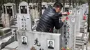 Seorang pria mengecat ulang batu nisan makam keluarga mereka saat festival Qingming di Shanghai (6/6). Festival tradisional Tiongkok ini dilaksanakan pada hari ke-104 setelah titik balik Matahari di musim dingin. (AFP/Johannes Eisele)
