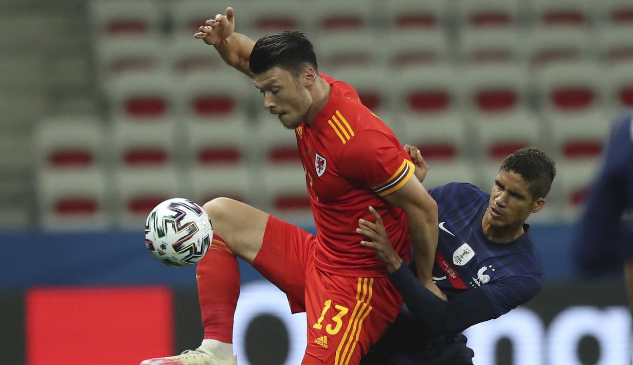 Gelandang Wales, Kieffer Moore (kiri) menguasai bola dibayangi bek Prancis, Raphael Varane dalam laga uji coba menjelang berlangsungnya Euro 2020 di Allianz Riviera Stadium, Nice, Rabu (2/6/2021). Wales kalah 0-3 dari Prancis. (AP/Daniel Cole)