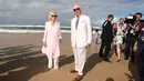 Pangeran Charles bersama istrinya, Duchess of Cornwall Camilla berjalan di atas pasir pantai saat mengunjungi Broadbeach di Gold Coast, Australia, Kamis (5/4). Istri Pangeran Charles itu terlihat berjalan tanpa alas kaki. (Mark Metcalfe/POOL/AFP)