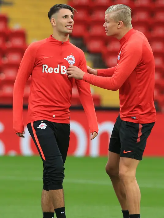 Penyerang Red Bull Salzburg, Erling Haaland (kanan) berbincang dengan rekannya Dominik Szoboszlai selama latihan tim di stadion Anfield, Inggris (1/10/2019). Remaja 19 tahun ini tampil sensasional mencetak hattrick di matchday pertama grup E Liga Champions melawan  Genk. (AFP Photo/Lindsey Parnaby)