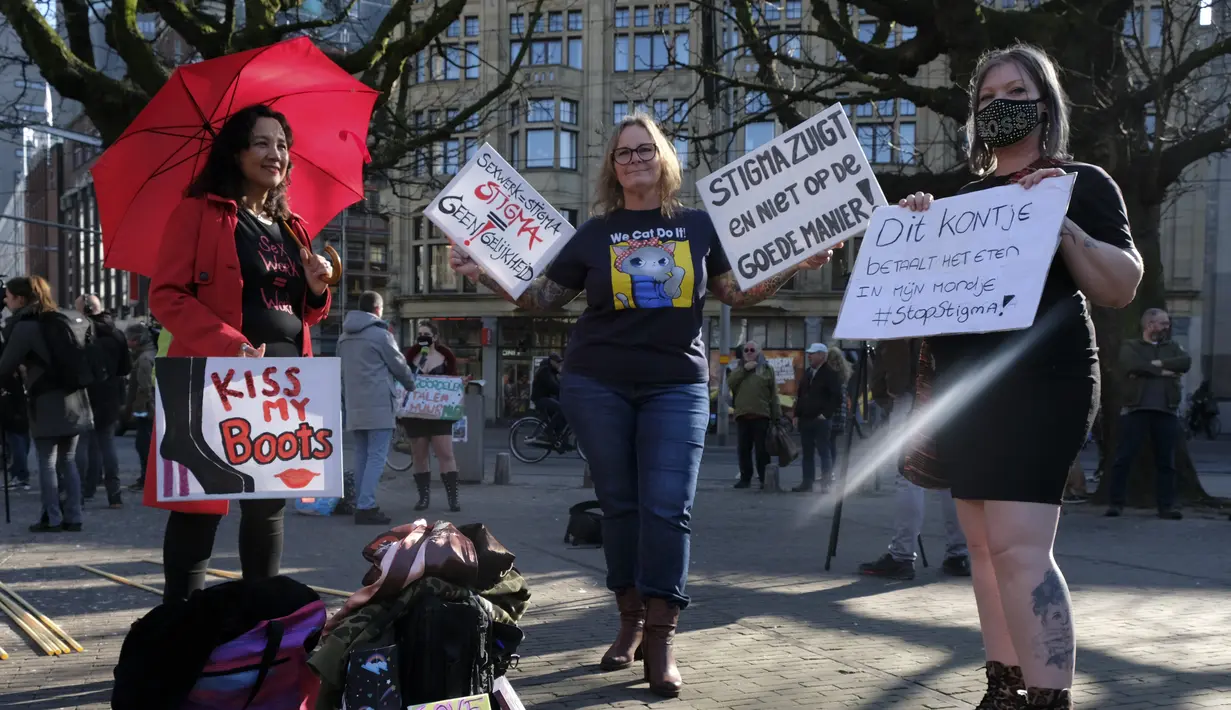 Para pekerja seks membawa plakat memprotes perlakuan dan stigma yang tidak setara selama demonstrasi di Den Haag, Belanda, Selasa (2/3/2021). Mereka berdemonstrasi di luar parlemen dalam protes terhadap penguncian keras virus corona oleh pemerintah. (AP Photo/Patrick Post)