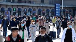 Orang-orang tiba di stasiun kereta api Beijing pada hari terakhir libur nasional "golden week" pada Kamis (7/10/2021). Liburan yang kerap disebut sebagai The Golden Week Holiday ini adalah peringatan berdirinya Republik Rakyat China pada tahun 1949. (JADE GAO / AFP)