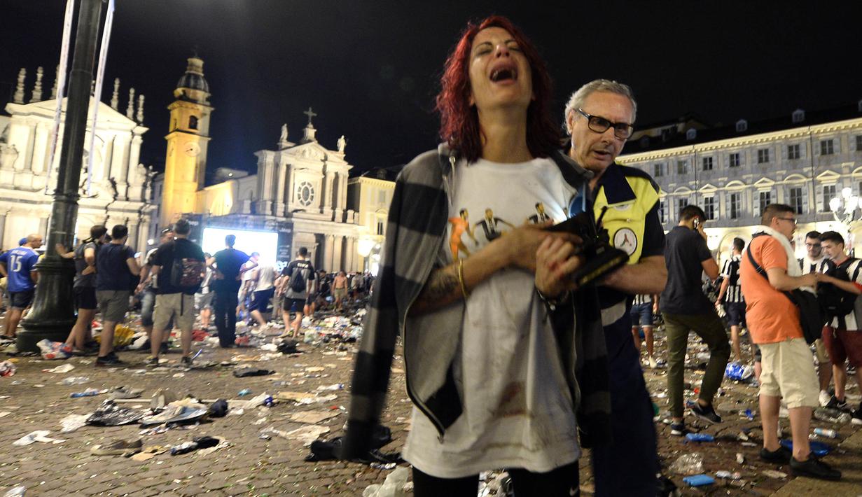Seorang wanita menangis usai terjadi ledakan saat nonton bareng final Liga Champions di Piazza San Carlo, Turin, Sabtu (3/6/2017). Acara nobar dipadati sekitar 20.000 supporter Juventus. (AFP/Massimo Pinca)