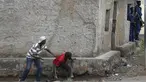 Pengunjuk rasa sembunyi dibalik dinding dengan membawa batu bersiap menyerang petugas di Bujumbura, Burundi, (20/5/2015). Kerusuhan dipicu protes terhadap Presiden Burundi Pierre Nkurunziza untuk upayanya menambah masa jabatan. (REUTERS/Goran Tomasevic)
