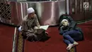 Jemaah membaca kitab suci Alquran dekat seorang pria yang tengah tertidur di Masjid Istiqlal, Jakarta, Selasa (7/5/2019). Umat muslim meningkatkan ibadah pada bulan suci Ramadan dengan membaca Alquran (tadarus), salat berjemaah, berdoa, dan zikir di masjid. (Liputan6.com/Faizal Fanani)