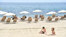 Orang-orang berjemur di Pantai Bogatell di Barcelona, Minggu (6/6/2021). Spanyol akan mengizinkan semua pelancong yang divaksinasi untuk mengunjungi negara itu mulai 7 Juni, dengan tujuan kembali menghidupkan industri perjalanan yang terpukul pandemi Covid-19. (Pau BARRENA/AFP)