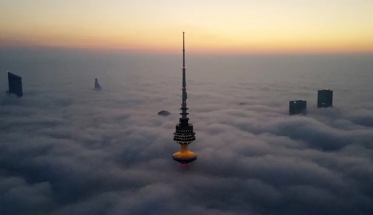 Foto udara memperlihatkan pemandangan Liberation Tower (depan) di tengah kabut tebal, Kuwait City, 21 Januari 2023. Liberation Tower tidak dapat diakses oleh publik karena kompleks bangunan ini menampung kantor-kantor pemerintah. (YASSER AL-ZAYYAT/AFP)