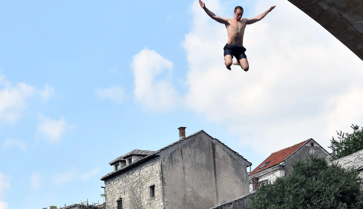 Peserta melompat dari Jembatan Old Mostar pada kompetisi menyelam tradisional ke-452 di Mostar, Bosnia, 29 Juli 2018. Penyelam berlari sebelum melompat dari jembatan, jatuh ke sungai dan terbang di udara seperti burung melakukan trik. (ELVIS BARUKCIC/AFP)
