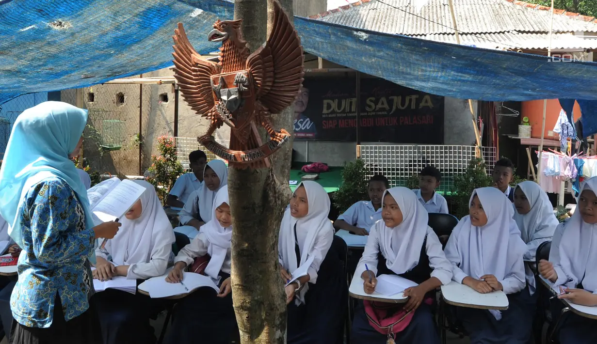 Guru mengajar siswa kelas 8 SMP  1 Cijeruk Terbuka di tempat belajar beratapkan terpal di halaman rumah warga di Kampung Cijeruk RT 002/005, Desa Palasari, Kecamatan Cijeruk, Kabupaten Bogor, Jawa Barat, Senin (2/9/2019). (merdeka.com/Arie Basuki)