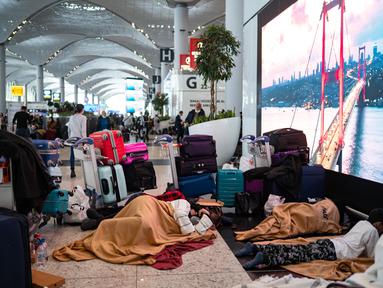 Penumpang yang terdampar menunggu di bandara Istanbul, di mana penerbangan dibatalkan karena badai salju dan hujan salju lebat, di Istanbul, Turki, pada 25 Januari 2022. Penutupan salah satu bandara tersibuk di Eropa ini akibat hantaman badai salju yang menghambat operasional. (Yasin AKGUL/AFP)