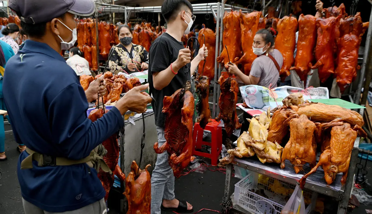 Pekerja membawa babi panggang di pasar menjelang Tahun Baru Imlek yang menyambut Tahun Macan di Phnom Penh, Kamboja, Senin (31/1/2022). Menyambut Tahun Baru Imlek, warga Kamboja mempersiapkan daging babi panggang untuk sajian makan. (AFP/Tang Chhin Sothy)