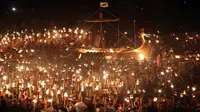 Anggota Jarl Squad mengelilingi replika kapal perang Viking sambil membawa obor selama festival Up Helly Aa Viking di Lerwick, Kepulauan Shetland, Skotlandia (31/1). Festival ini secara resmi digelar pertama kali pada tahun 1880. (Jane Barlow/PA via AP)