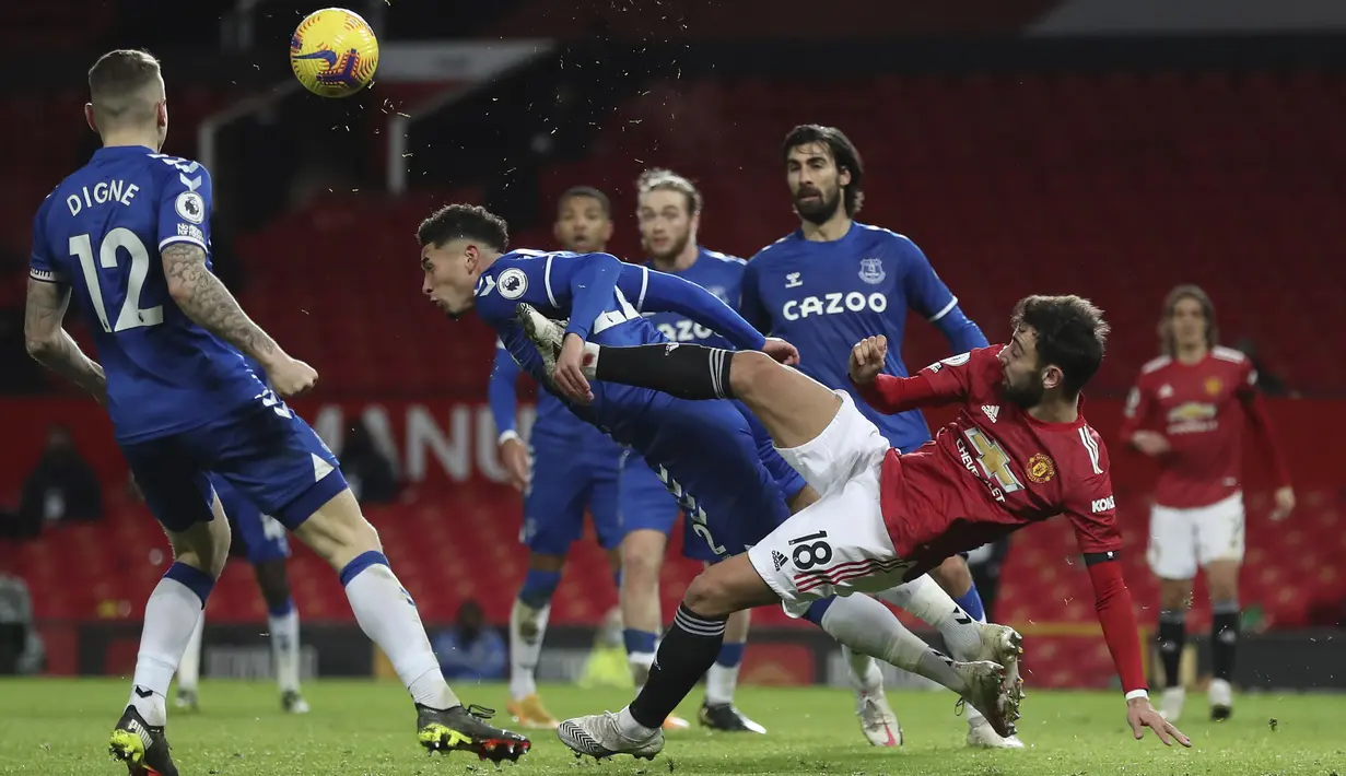 Gelandang Manchester United (MU), Bruno Fernandes berebut bola dengan bek Everton, Ben Godfrey pada laga pekan ke-23 Liga Inggris 2020/2021 di Old Trafford, Minggu dinihari WIB (7/2/2021). MU hanya mampu bermain imbang 3-3 saat menjamu Everton. (Martin Rickett/Pool via AP)