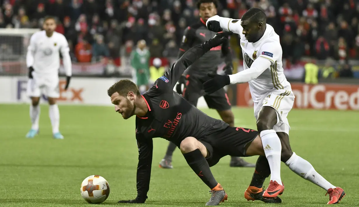 Aksi pemain Arsenal, Shkodran Mustafi (kiri) mengecoh pemain Ostersund, Ken Sema pada babak 32 besar Liga Europa di Jamtkraft Arena, Ostersund, Swedia (15/2/2018). Arsenal menang 3-0. (AFP/Robert Henriksson/TT News Agency)