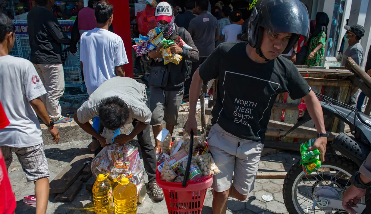 Warga menjarah kebutuhan pokok dari toko swalayan setelah gempa kuat dan tsunami mengguncang Kota Palu di Sulawesi Tengah, Minggu (30/9). Warga terpaksa mengambil karena mereka juga membutuhkan makanan dan air bersih. (AFP PHOTO/BAY ISMOYO)