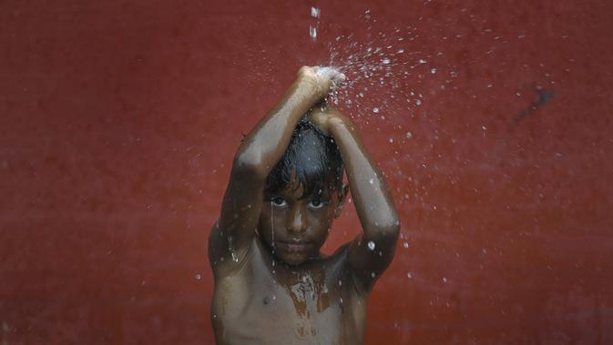 Seorang anak mandi dengan air hujan di La Guaira, Venezuela pada 26 Juli 2020, di tengah pandemi virus corona COVID-19 ketika sisa-sisa Badai Tropis Gonzalo melewati Karibia. (AP Photo / Matias Delacroix)