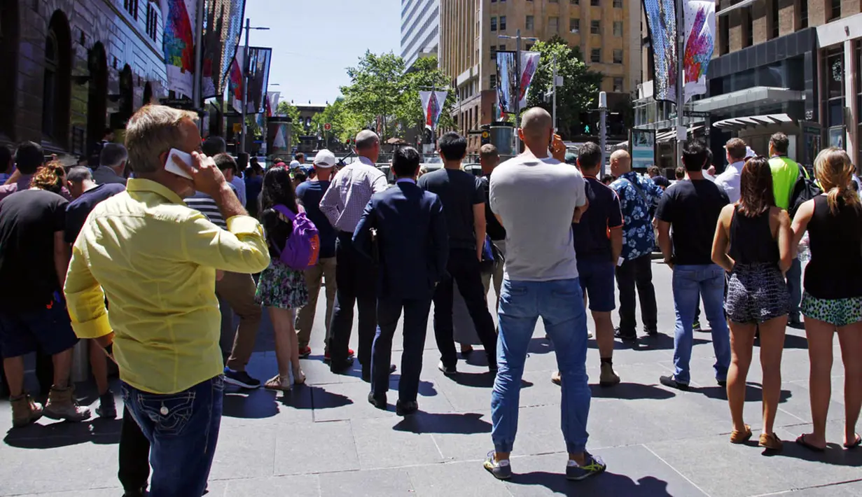 Beberapa orang berdiri di dekat lokasi penyanderaan di kafe Lindt, Sydney, Australia (15/12/2014). Puluhan sandera terperangkap di dalam kafe Lindt di Sydney, Australia. (REUTERS/David Gray)