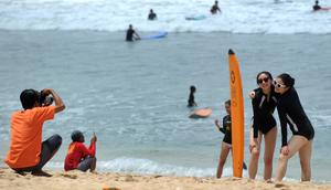 Dua turis wanita berpose saat difoto di pantai Kuta di pulau pariwisata Indonesia di Bali (4/1). Daerah ini merupakan tujuan wisata turis mancanegara dan telah menjadi objek wisata andalan Pulau Bali sejak awal tahun 1970-an. (AFP Photo/Sony Tunbelaka)