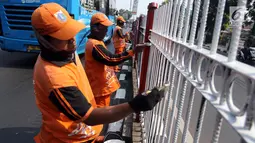 Petugas PPSU Kelurahan Kramat Jati melakukan pengecatan ulang pagar pembatas Jalan Raya Bogor, Jakarta, Selasa (17/7). Upaya penataan sekaligus mempercantik kawasan terus dilakukan jelang Asian Games dan Hari Kemerdekaan RI. (Liputan6.com/Arya Manggala)