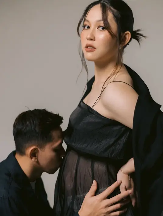 Foto pertama, keduanya tampak mengenakan pakaian serba hitam. Ribka tampil elegan dengan atasan hitam sheer yang memerlihatkan baby bumpnya. Dipadukan rok panjang sheer warna putih. [@venemapictures]