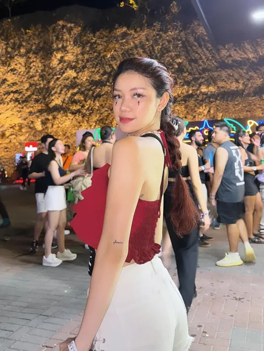 Regina Phoenix tampil memesona dengan ruffle halter top merah dan bawahan putih. Makeup wajah dengan beads sebagai aksen bisa kamu tiru nih! [@fuji_an/@rachelvennya/@reginaaphx/lulalahfah]