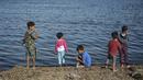 Anak-anak berdiri di tepi laut di kamp pengungsi Kara Tepe, di pulau Lesbos di timur laut Aegean, Yunani (14/10/2020).  Sekitar 7.600 pengungsi dan migran telah menetap di kota tenda baru setelah kebakaran yang menghancurkan kamp pengungsi Moria. (AP Photo/Panagiotis Balaskas)