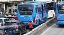 Pedagang asongan menjajakan barang dagangannya di persimpangan lampu merah di Jakarta, Jumat (22/2). Keahlian yang terbatas menyebabkan sebagian orang harus bekerja di tengah padatnya kendaraan Ibukota. (Liputan6.com/Immanuel Antonius)