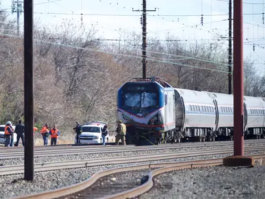 Personel darurat menyelidiki lokasi kereta Amtrak yang tergelincir setelah menabrak sebuah backhoe di dekat Philadelphia, Amerika Serikat, Minggu (3/4). Dua orang tewas dan 30 lainnya mengalami luka-luka akibat kejadian ini. (Mark Makela/Getty Images/AFP)