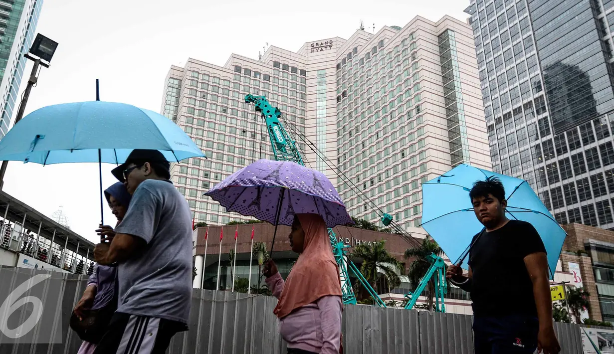 Sejumlah warga menggunakan payung saat menghadiri Car Free Day di Bundaran HI, Jakarta, Minggu (13/11). Meski gerimis di kawasan tersebut mereka tak surut untuk berolahraga. (Liputan6.com/Faizal Fanani)