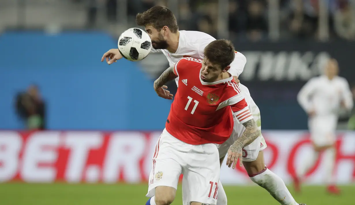 Duel pemain Rusia, Fedor Smolov (kanan) dan pemain Spanyol, Gerard Pique pada laga persahabatan di St.Petersburg, Russia, (14/11/2017). Spanyol bermain imbang 3-3 lawan Rusia. (AP/Dmitri Lovetsky)
