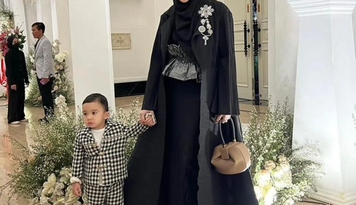 Zaskia Sungkar memilih dress hitam yang dipadukan obi belt dan long coat di resepsi Kiky Saputri. [@zaskiasungkar15].