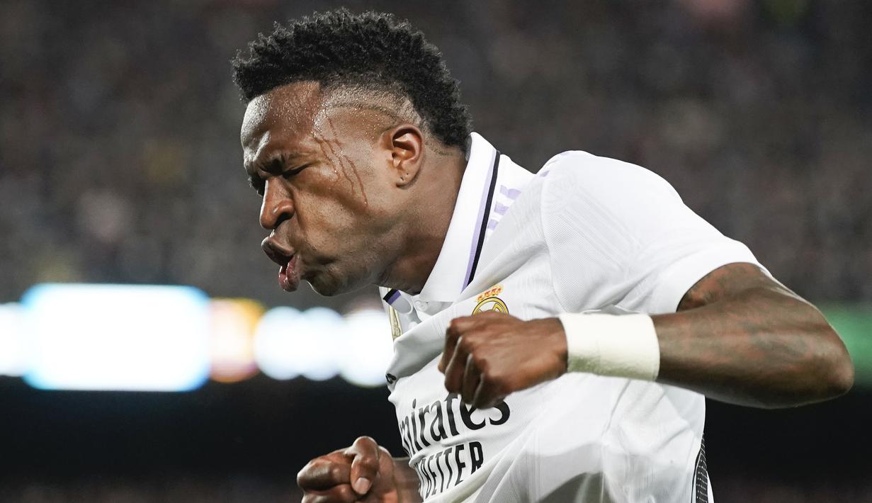 Pemain Real Madrid, Vinicius Jr melakukan selebrasi setelah tendangannya salah diantisipasi oleh pemain Barcelona, Ronald Araujo yang berujung menjadi gol pada laga pekan ke-26 Liga Spanyol 2022/2023 di Camp Nou, Barcelona, Senin (20/03/2023). Blaugrana menang dengan skor 2-1 pada pertandingan yang bertajuk El Classico tersebut. (AP Photo/Joan Mateu)