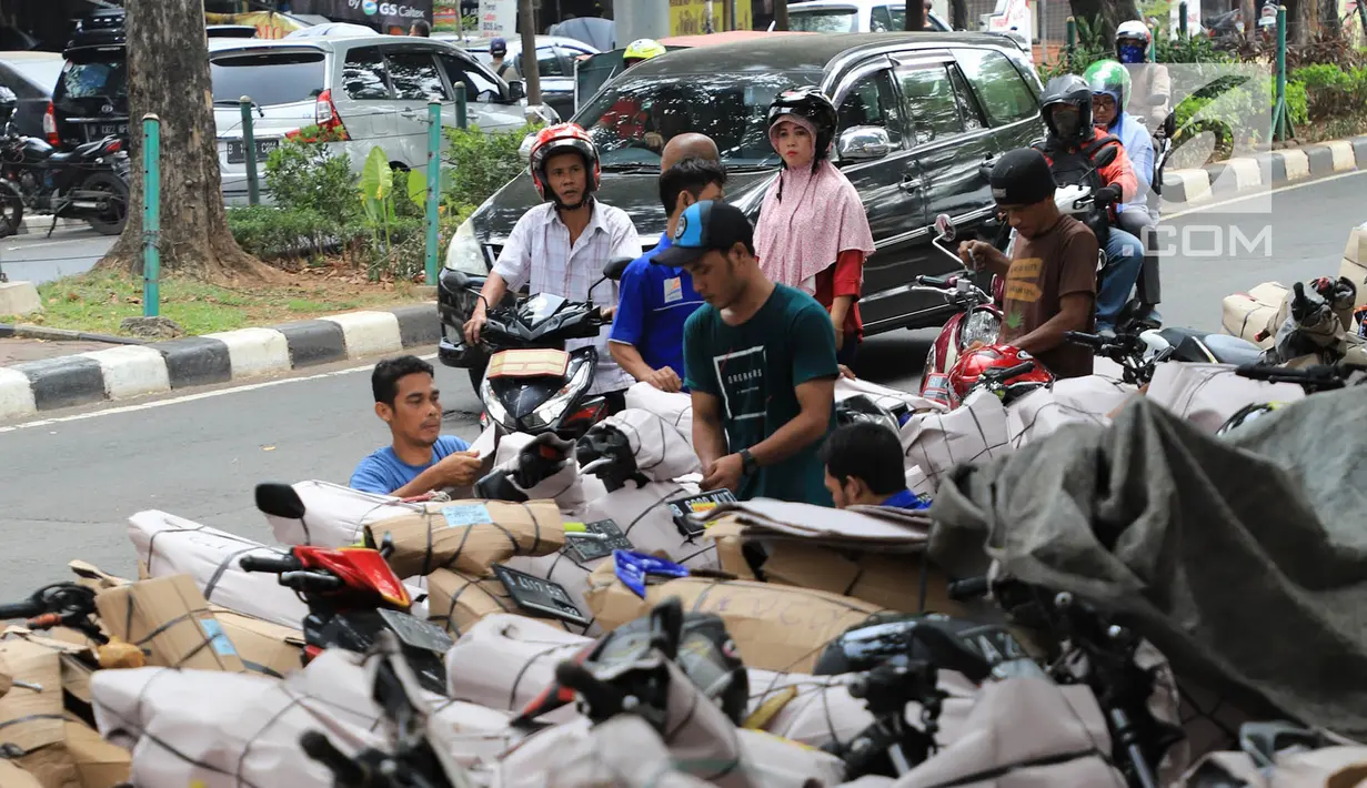 Pekerja membungkus sepeda motor yang akan dikirim di Stasiun Pasar Senen, Jakarta, Selasa (5/6). Jasa pengiriman motor ke daerah meningkat dua kali lipat jelang arus mudik dan Hari Raya Idulfitri 2018. (Liputan6.com/Arya Manggala)