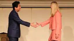 Ivanka Trump (kanan) berjabat tangan dengan PM Shinzo Abe saat acara Majelis Wanita Sedunia (WAW!) di Tokyo, Jepang (3/11). Ivanka berpidato di Majelis Wanita Sedunia jelang kunjungan luar negeri ayahnya ke Jepang. (AFP Photo/Pool/Eugene Hoshiko)