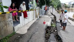 Sejumlah warga mengamati jalan retak di Kelurahan Kebon Manggis, Kecamatan Matraman, Jakarta Timur, Jumat (16/2). Tak hanya retak, jalan yang tepat berada di pinggir anak sungai Ciliwung itu juga sempat mengalami longsor. (Liputan6.com/Johan Tallo)