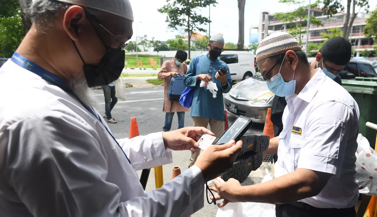 Petugas memeriksa pendaftaran umat muslim untuk salat Jumat usai pencabutan pembatasan Covid-19 di Masjid Al-Istighfar, Singapura, Jumat (26/6/2020). Masjid-masjid di Singapura menyediakan 2 sesi setiap Jumat dengan kuota yang diperbolehkan adalah 50 orang pada satu waktu. (Roslan RAHMAN/AFP)