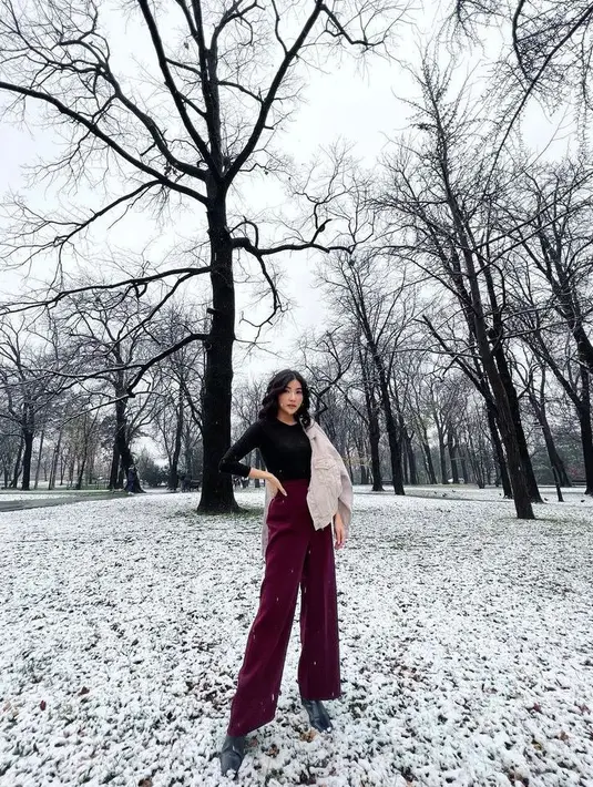 Selain berdaster, Sarwendah juga tampil elegan dengan pakaian musim dingin. Seperti potret ini, ia terlihat stylish dalam paduan busana longsleeve warna hitam dengan celana cutbray merah maroon dan jaket warna putih. (Instagram/sarwendah29).